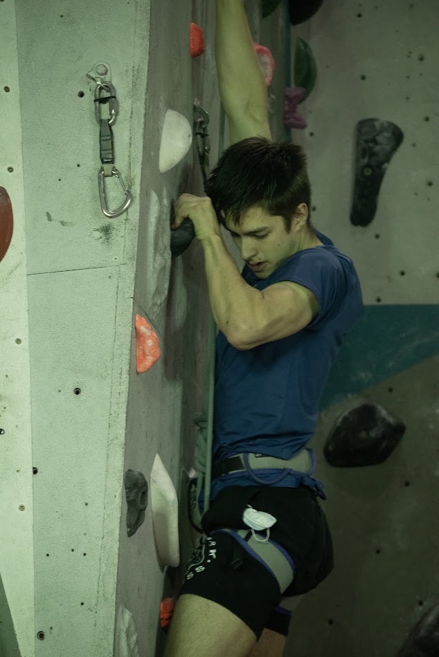 A man climbing a sport route looking down